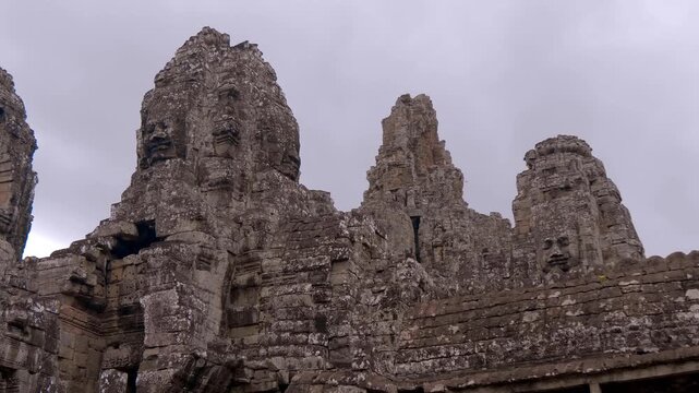 Massive heads of Bodhisattva Avalokiteshvara made of stone on the tower of Bayon Temple in Angkor Wat Park, Cambodia. Shot in motion