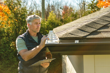 Plakat man standing on steps inspecting house roof