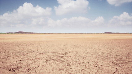 A vast dry landscape stretches out under a bright blue sky filled with fluffy clouds. The cracked earth tells a story of drought, emphasizing the need for rain in this arid environment.