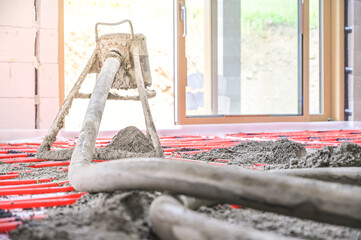 This image illustrates the pouring of concrete in a modern construction space, showcasing the use of machinery and tools for effective flooring installation