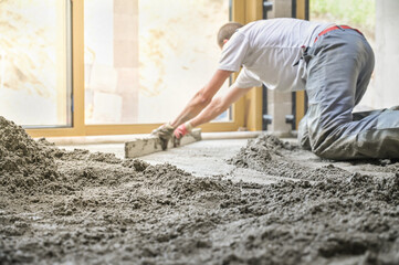 A construction worker expertly levels a freshly poured concrete floor, showcasing skill and meticulous attention to detail in the process of creating a smooth surface