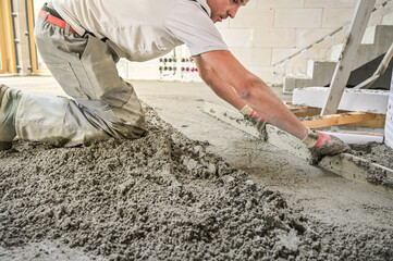 A construction worker expertly levels a freshly poured concrete floor, showcasing skill and meticulous attention to detail in the process of creating a smooth surface
