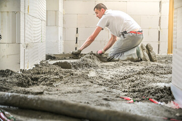 A construction worker expertly levels a freshly poured concrete floor, showcasing skill and meticulous attention to detail in the process of creating a smooth surface