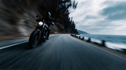 Motorcycle rider in motion on a scenic coastal highway with ocean and cliffs