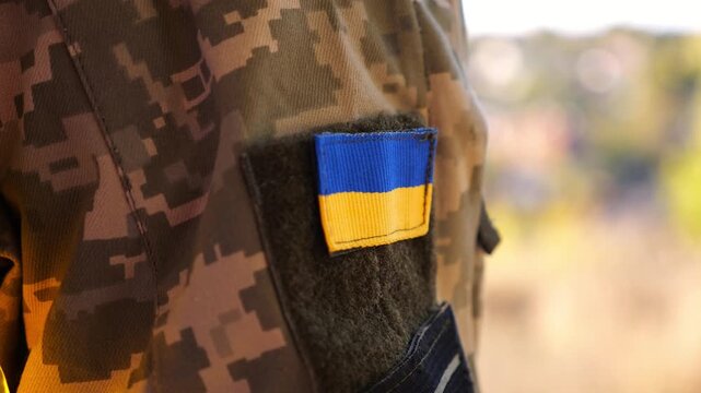 Close up of military blue-yellow chevron on shoulder of soldier at countryside. This emblem embodies the unbreakable spirit and pride of the ukrainian people. Concept of invasion resistance.