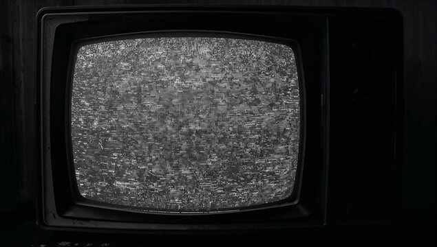 Displaying CRT television set showing black-and-white static on dark tabletop in wood-paneled room - Powered by Adobe