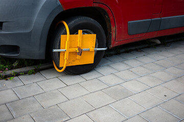 Yellow wheel clamp on car parked in forbiden place. Penalty for breaking the urban parking rules. ...