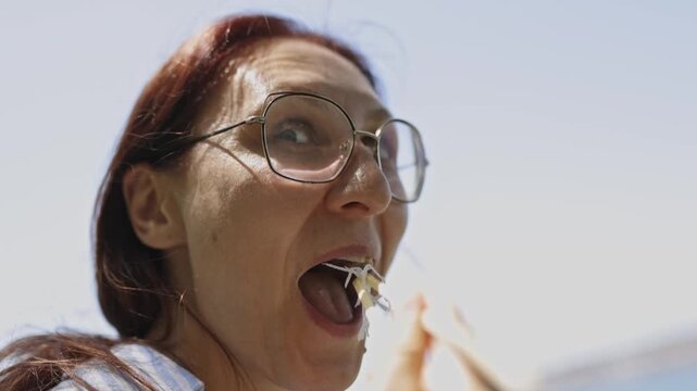 Woman with glasses teasingly eating a scallion