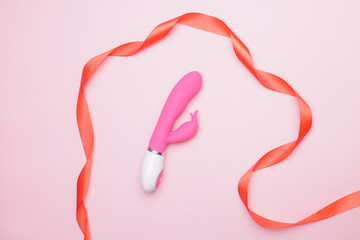 Pink pink vibrator personal massager for woman with ribbon on pink background