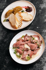 Sliced beef with capers and toasted bread garnish on elegant plates