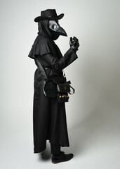 Naklejka premium Plague Doctor Full length walking Silhouette Portrait of Gothic Halloween Character with Beak Mask, Black Cloak on White Studio Background, Dramatic Dark Costume and Fantasy Horror figure