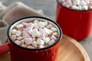 Hot chocolate drink with marshmallows in red mug on wooden table