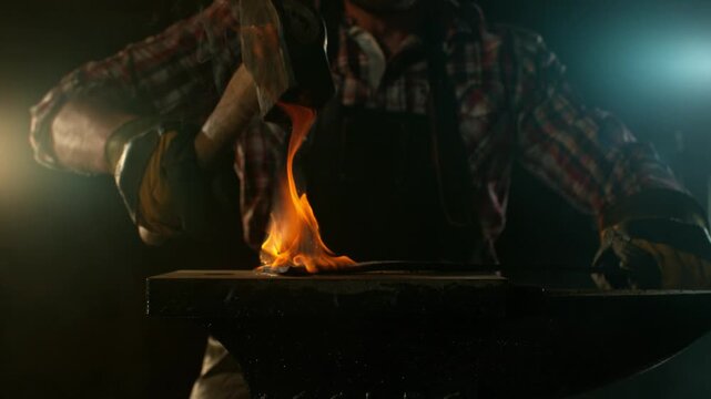 Close-up of blacksmith forging glowing hot iron on anvil with flying sparks. Super slow motion filmed on high-speed cinema camera at 1000 fps