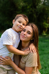Naklejka premium Image of happy mother and son outside in public park. Ideal for themes of parenting, motherhood and family relationships