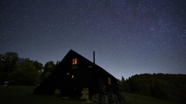 Peaceful starry night sky with countless stars above a wooden mountain hut in spring nature