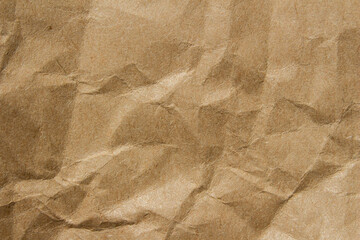 Obraz premium Brown crumpled kraft paper texture with deep folds and creases