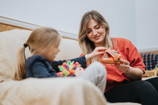 Cheerful interaction between a woman and a child spending quality time playing with toys on a comfortable couch, showcasing a heartwarming and nurturing atmosphere filled with happiness and connection