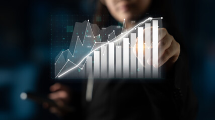 A business professional engages in data analysis by visualizing financial graphs and charts,...