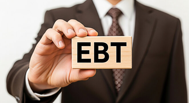 Man in suit holds wooden block displaying "EBT" for electronic benefits transfer program awareness and financial assistance information
