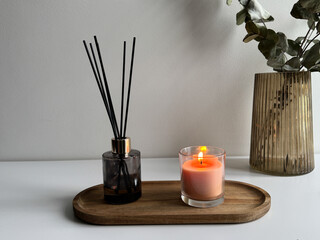 Cozy Home Decor with Candle and Aroma Diffuser. Minimal Interior — Burning Candle and Eucalyptus Vase