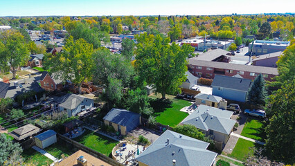 Fototapeta premium Washington Virginia Vale in Denver, Colorado, showing single-family homes with diverse roofs, patios and mature trees in early fall. Commercial buildings and parking lots frame the background