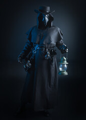 Naklejka premium Gothic Plague Doctor with Lantern, Halloween Costume Character in Black Cloak and Bird Mask. Dark Studio Portrait with Atmospheric Lighting and Mysterious Fantasy Horror figure