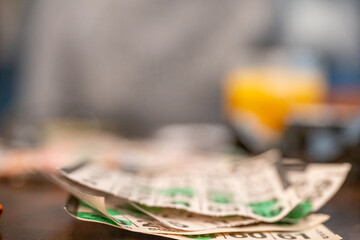 Collection of lottery tickets on a wooden table with blurred background in a cozy setting