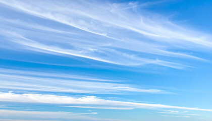 Wispy cirrus clouds streaking across a bright blue sky