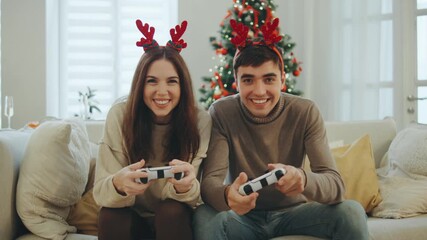 Couple enjoying video games at home during the Christmas season with festive decorations and joyful atmosphere