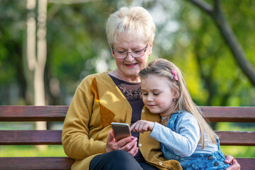 Grandmother and granddaughter using smartphone together in park