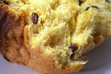 Macro shot of bread texture with raisins and candied orange peel. Detailed close-up of traditional sweet pastry showing soft dough and rich ingredients. Panettone or easter cake.