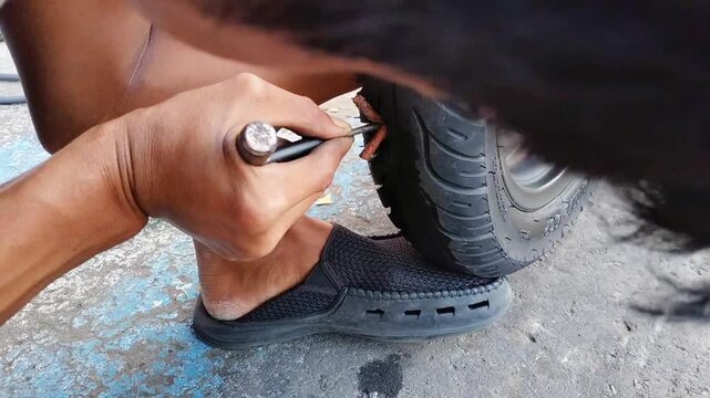 Rider use a tire plug kit and trying to fix a hole in tire's sidewall ,Repair a motorcycle flat tire in the garage. motorcycle maintenance and repair concept