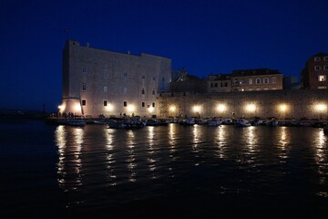 Blue hour view of Dubrovnik Old Town harbor with reflections on the sea, Croatia