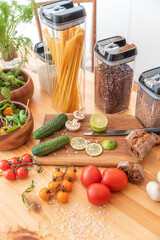 Pasta with tomato sauce and basil on kitchen worktop, vegetables and utensils all around