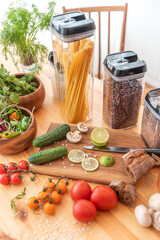 Pasta with tomato sauce and basil on kitchen worktop, vegetables and utensils all around
