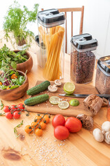 Pasta with tomato sauce and basil on kitchen worktop, vegetables and utensils all around