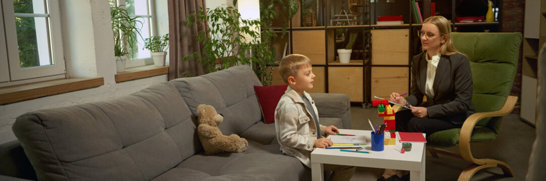 Boy talking with psychologist during therapy session surrounded by learning tools. Concept of child psychology, healthcare communication for emotional growth and cognitive development. Banner