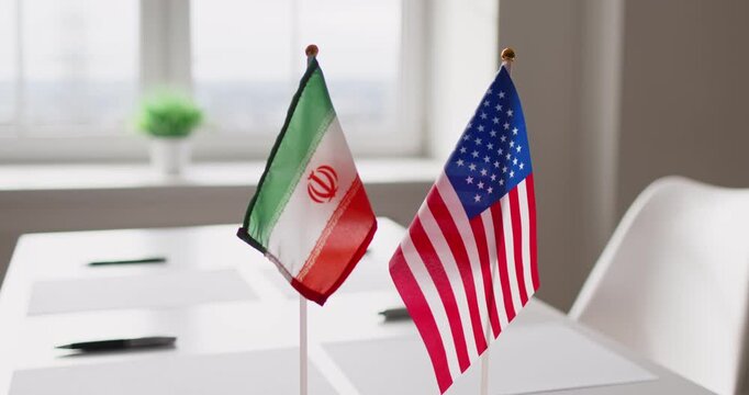 Flags diplomacy negotiations meeting partnership dialogue. Desk flags of Iran and USA on a conference table suggest geopolitics and agreement talks. Concept: international partnership and talks.