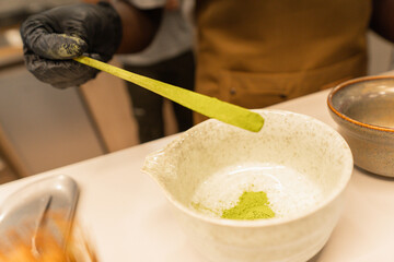 Hand preparing matcha green tea powder in bowl