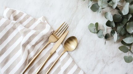 Golden cutlery on striped napkin with leafy sprigs, top-down view for culinary uses