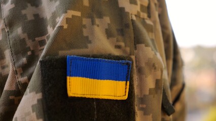 Close up of military blue-yellow chevron on shoulder of soldier at countryside. This emblem embodies the unbreakable spirit and pride of the ukrainian people. Concept of invasion resistance
