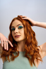 Fototapeta premium Vibrant redhead woman showcases bold makeup look in studio setting