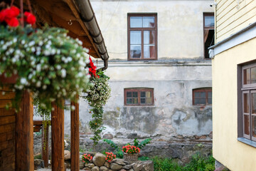 Charming courtyard scene featuring vibrant hanging flowers, rustic wooden beams, and aged stone walls, creating a serene atmosphere with natural beauty and inviting ambiance