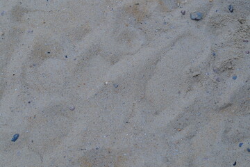 A ground level close-up shows the beach sand texture and scattered pebbles.