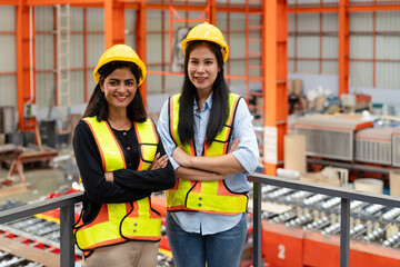 portrait of female engineer supervisor and technician standing together in safety wear and helmet  in production line, team of diverse workers working together at industrial manufacturing factory