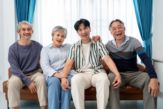 asian family group of senior man woman and son smiling sitting together in living room. home caregiver nurse visit retirement patient for health check up recovery process medical service