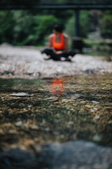 A person sits in a relaxed position in a serene outdoor environment near a river, emphasizing calmness and mindfulness.