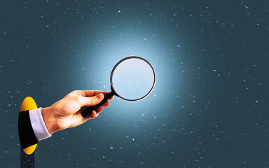A hand with a magnifying glass appears from a hole in the paper.