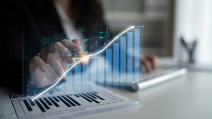 A professional analyzes financial data with a digital graph overlay, highlighting trends and growth while seated in a modern office workspace. Impute