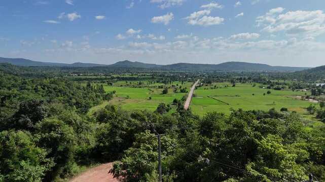 Beautiful 4K aerial footage showcasing lush rice fields, scenic mountains, and a winding countryside road connecting Kalasin and Sakon Nakhon in northeastern Thailand.